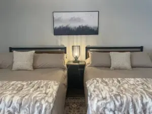 Twin bedroom with yellow lamp and a painting